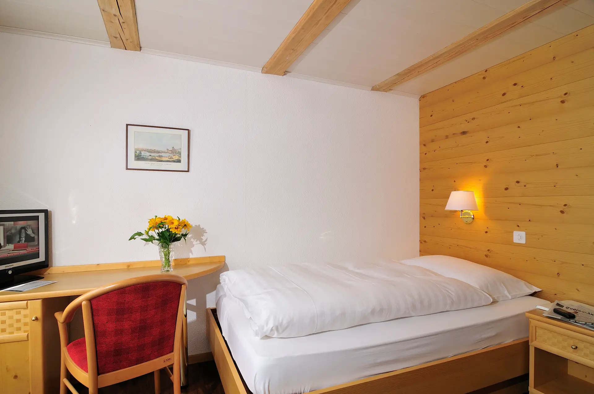 Ein gemütliches Einzelzimmer im Hotel Chalet Swiss mit traditionellem Schweizer Design, einem bequemen Bett und warmer Atmosphäre – perfekt für Alleinreisende