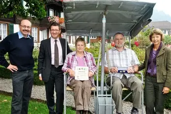 Richard und Carol Jenkinson erhalten den Goldenen Schlüssel für 10 Jahre Treue zum Hotel Chalet Swiss von Gemeinderätin Ingrid Hofer am 17. September 2009, mit Stefan Otz von Interlaken Tourismus im Hintergrund.